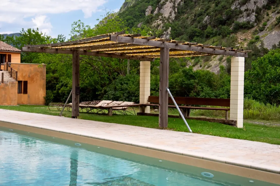La piscine du domaine et sa pergola ombragée au pied des falaises